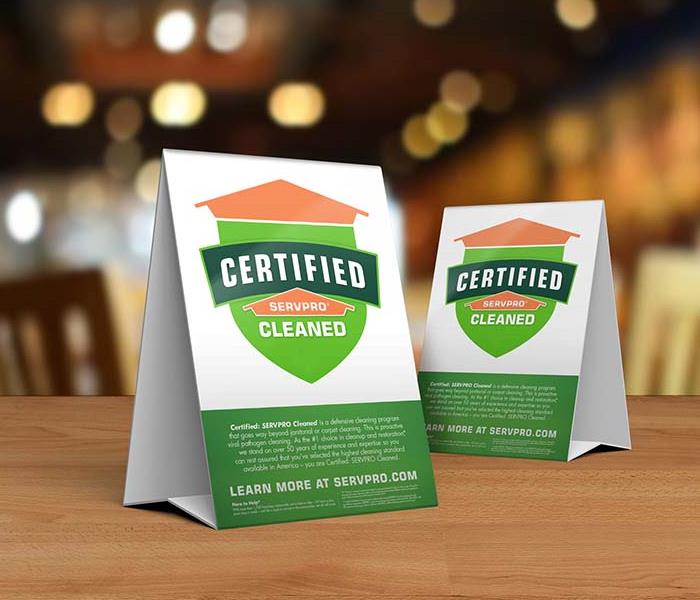  Table tent signs describing the Certified: SERVPRO Cleaned program on top of a wooden table.
